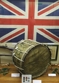 Photograph of main display case containing large drum from Boer War and flags.