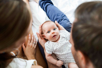A baby laughing at a book being read by their mother