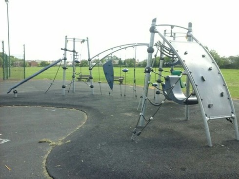 Multi-play unit with play ropes, climbing panel, seats and balance beam situated on wetpour
