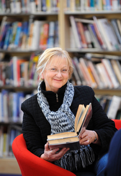 a picture of a woman in a library holding a book