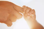 Picture of a baby holding its mother's finger